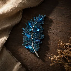 Vista detallada de un elegante broche de hoja de strass azul sobre superficie de madera.