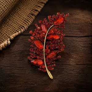 Primer plano detallado de un elegante broche de hoja de cristal rojo en madera oscura.