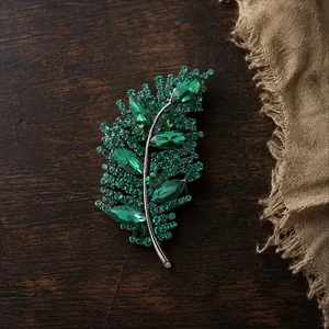 Detalle macro de un elegante broche de hoja de cristal verde esmeralda en madera