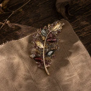 Primer plano de un broche de hoja dorada vintage con pedrería marquise de colores