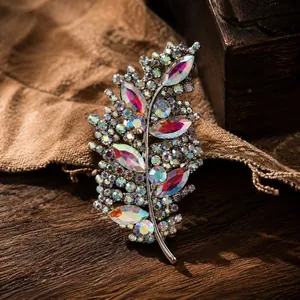 Vista detallada de un elegante broche de hoja con pedrería AB irisada sobre fondo rústico