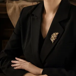Elegante broche de hoja dorada con diamantes de imitación brillantes en una chaqueta negra.