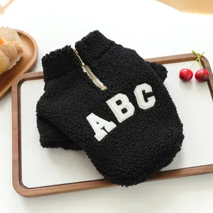 Detailed view of a cozy black sherpa fleece dog jacket with white ABC embroidery detail.