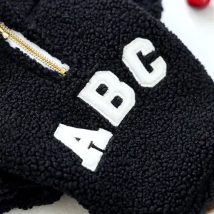 Close-up of black sherpa dog jacket with white ABC embroidery and golden zipper