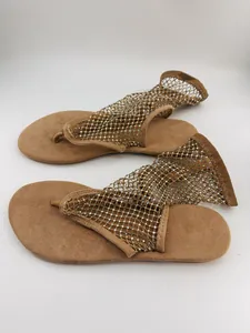 Détail des sandales à entre-doigt plates beiges avec empeigne en maille et strass brillants