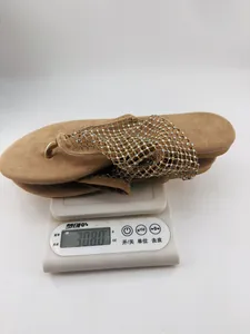 Mesure du poids de sandales à strass pesant 308 grammes sur une balance blanche