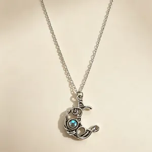 Close-up of retro silver moon pendant necklace with central blue moonstone detail