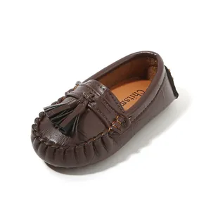 Detailansicht der dunkelbraunen Leder-Slipper für Kinder mit weicher Sohle und Troddel