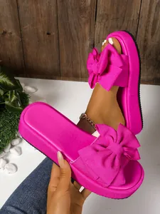 Sandalias de plataforma rosa fucsia con lazos de gran tamaño y suelas bastante gruesas.