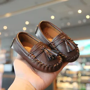 Nahaufnahme brauner Kinder-Slipper mit Quasten und stilvoller Krokodil-Struktur