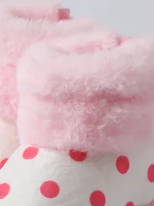Detailansicht von rosa Kunstfellbesatz und roten Punkten an Babystiefeln