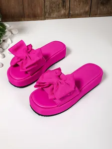 Primer plano de sandalias con plataforma rosa fucsia y un gran lazo decorativo de tela