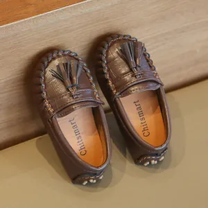 Detailansicht brauner Slipper für Kleinkinder mit Krokoprägung und dekorativen Quasten.