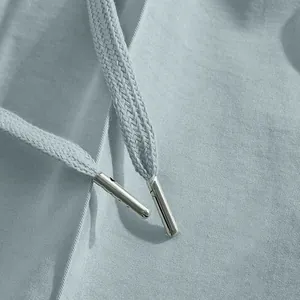 Close-up detail of light blue casual pants showing woven drawstring and metal aglets