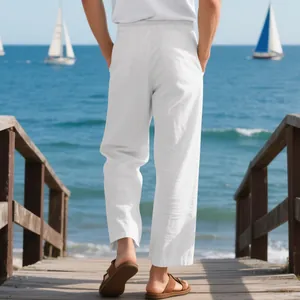 Back view of premium loose-fit white linen trousers for men in a scenic beach boardwalk setting