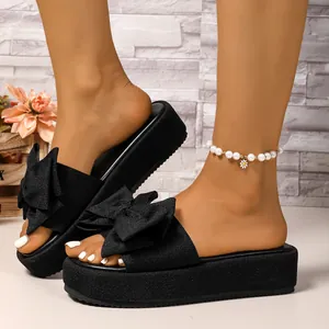 Sandalias de plataforma negras para mujer con un gran lazo decorativo para la playa.