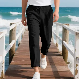 Men's loose black linen trousers walking on a beach pier, casual summer beach style