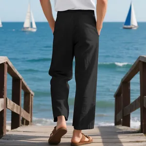 Detailed back view of men's loose black linen pants worn at a scenic beach pier