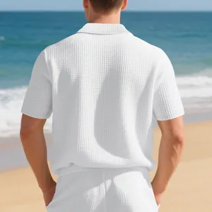Vue arrière d'un polo blanc minimaliste en maille gaufrée pour homme sur une plage ensoleillée