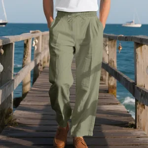 Men's loose sage green linen pants for beach casual style on a wooden pier.