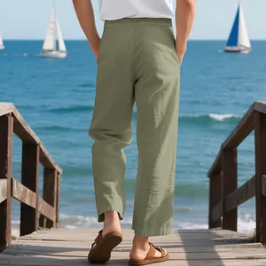 Rear view of men's loose linen beach trousers in olive green on a wooden pier