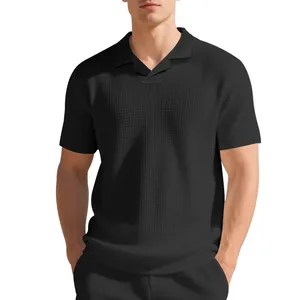 Vue détaillée d'un polo noir en maille gaufrée avec un col Burke minimaliste.