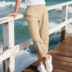 Men's loose linen casual pants shown in a relaxing beach setting with sneakers.