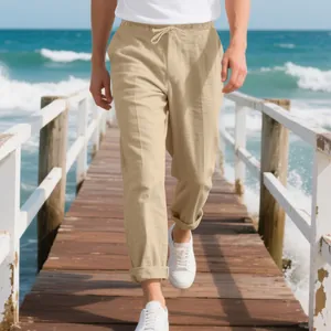 Detail shot of men's loose khaki linen pants being worn on a sunny beach pier walk