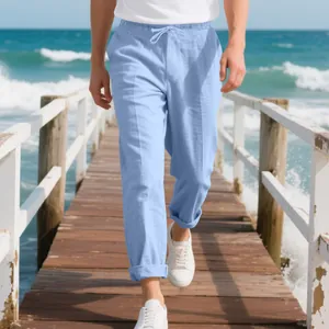 Close-up view of light blue men's loose linen beach pants on a scenic ocean wooden pier