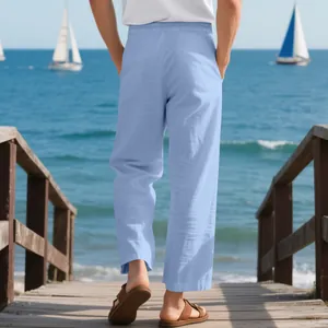 Back view of premium men's loose light blue linen beach pants on a wooden seaside pier