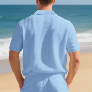 Vue arrière détaillée d'un polo pour homme bleu ciel en maille gaufrée sur la plage
