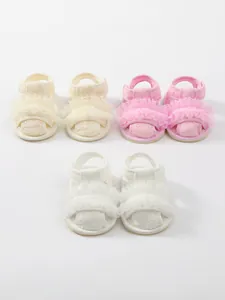 Gedetailleerde weergave van drie paar geborduurde babysandalen met kanten randen.