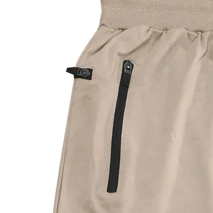 Detailansicht der khakifarbenen Herren-Jogginghose mit schwarzer Reißverschlusstasche.