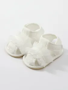 Gedetailleerd overzicht van witte baby meisje wandelsandalen met kant en borduurwerk