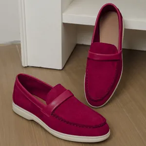 Detailed view of burgundy suede slip-on loafers featuring a flat white rubber sole