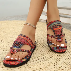 Detailansicht von böhmisch gemusterten flachen Flip-Flops auf einer Strohmatte