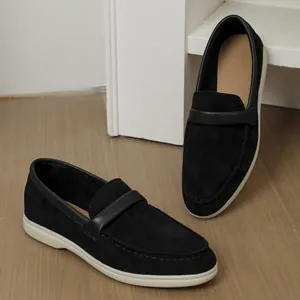 Macro view of stylish black suede loafers with white soles on elegant wooden floor