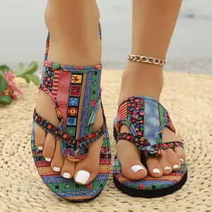 Detailansicht farbenfroher Bohemian-Zehentrenner auf einer Strohmatte für den Strand.