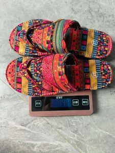 Bunte böhmische flache Flip-Flop-Hausschuhe auf einer Waage für Gewichtsangaben