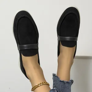 Close-up view of elegant black suede slip-on loafers with leather strap detail on feet