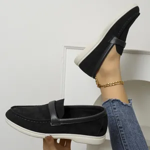Detail of black suede slip-on loafers showing comfortable flat soles and vintage design