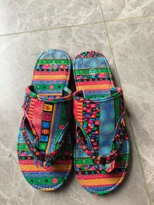 Draufsicht auf bunte flache Flip-Flop-Sandalen mit ethnischem Muster auf Fliesen