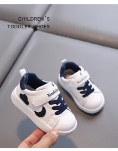 Detailed view of white leather toddler shoes with navy blue accents and velcro strap