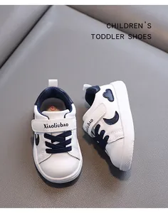 Detailed view of white toddler walking shoes with navy heart patterns and velcro strap