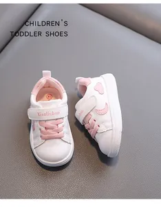 Detailed view of white toddler walking shoes with pink accents and velcro straps.
