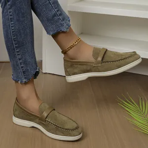 Detailed macro view of women's olive green suede loafers worn on feet in a casual setting