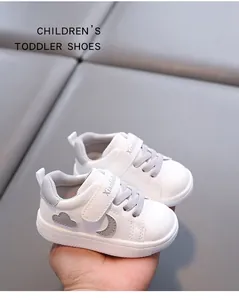 Detail view of white toddler walking shoes with grey cloud and moon decorative patches.