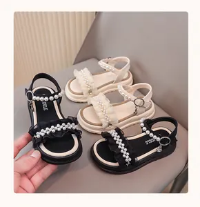 Details of black and white girls' sandals with pearls and ruffle trim.