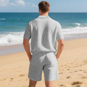 Back view of a man wearing grey waffle knit summer polo and shorts set on a beach