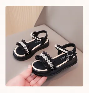 Detail view of black girls' sandals decorated with elegant pearls and soft ruffles